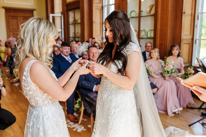 Two brides hold a quaich at the top of the aisle 