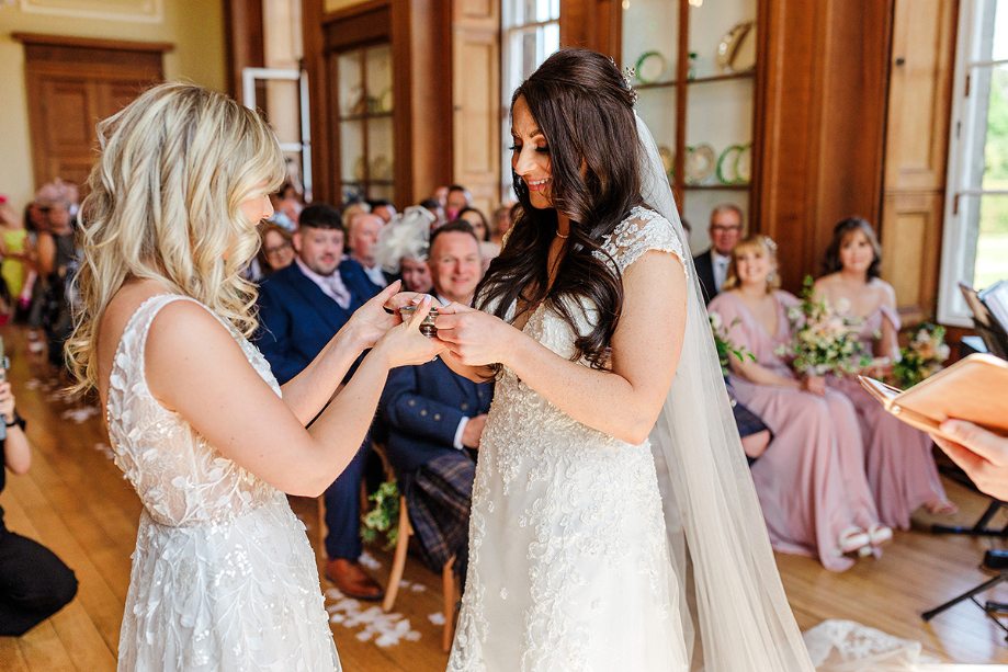 Two brides hold a quaich at the top of the aisle