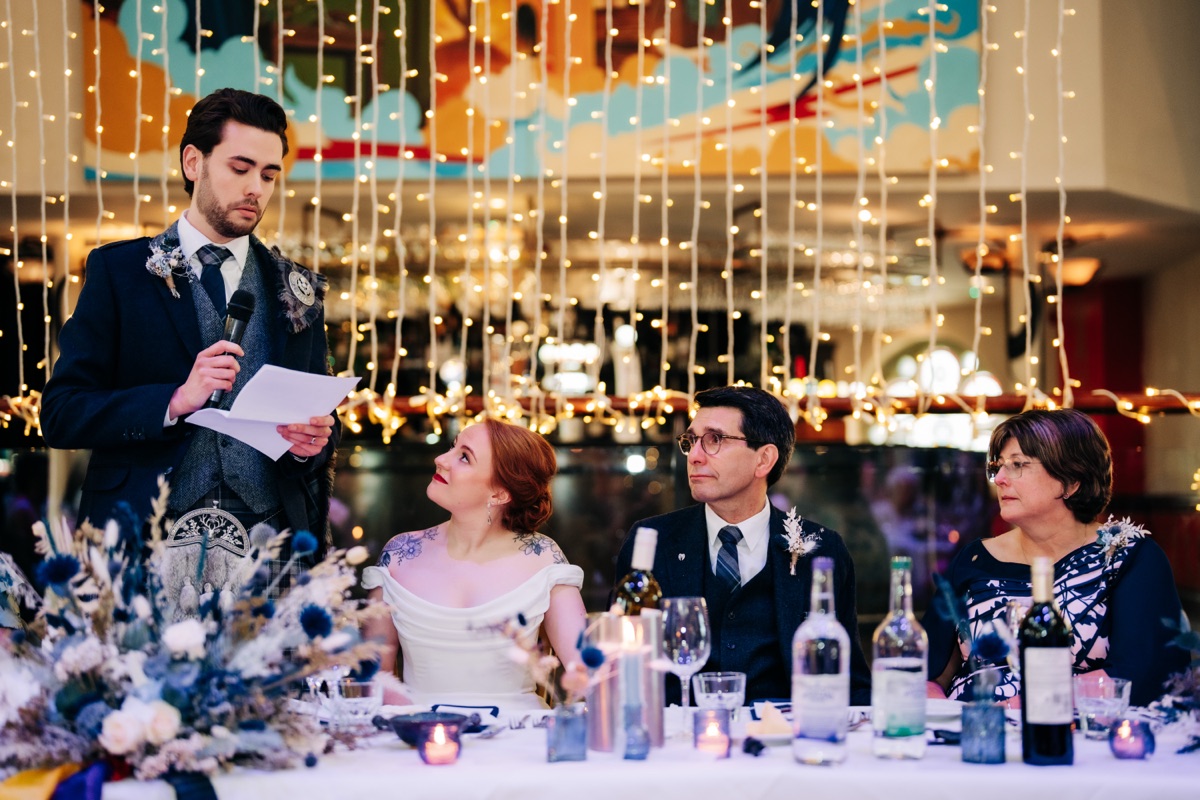 Groom James delivers his wedding speech at Òran Mór in Glasgow, while bride Robyn looks on from the top table.