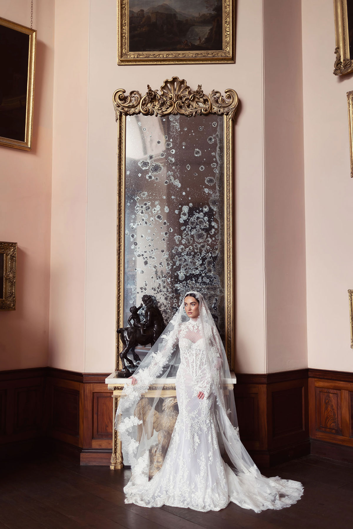 Lace wedding dress styled in front of an antique mirror and pink gallery walls at Gosford House.