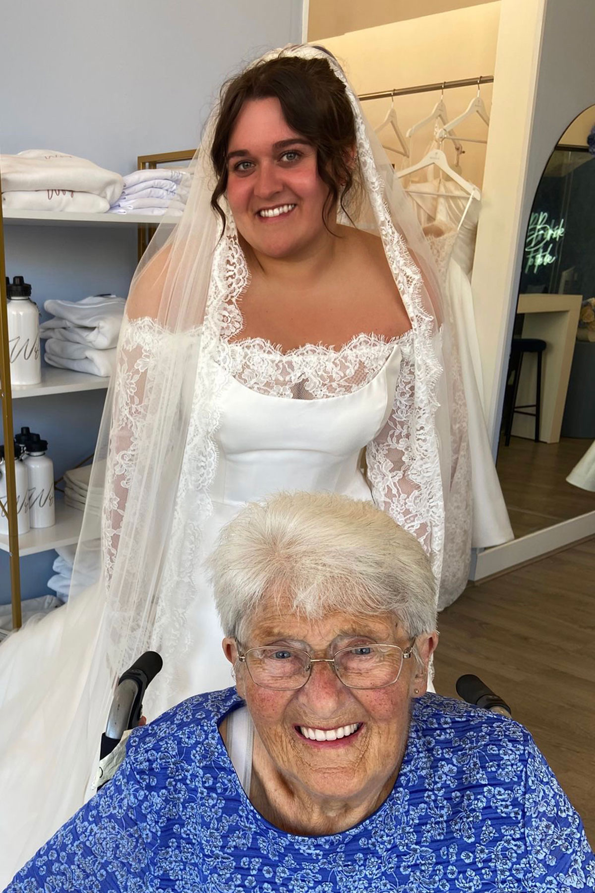 a smiling bride wearing her wedding dress with gran in wheelchair