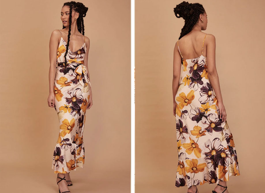 A woman wearing a long cream dress with a yellow and brown floral print