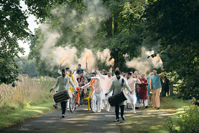 A group of people walking down a path with fire flares.