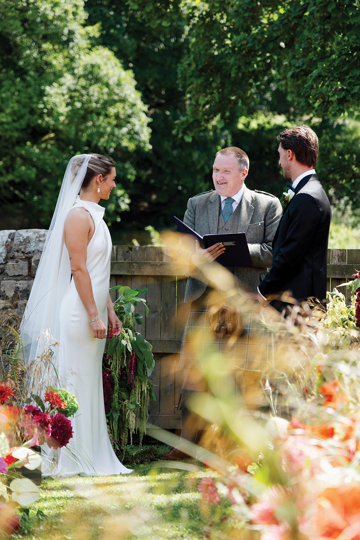 Bride and groom smiling during an outdoor garden wedding ceremony with a Scottish celebrant