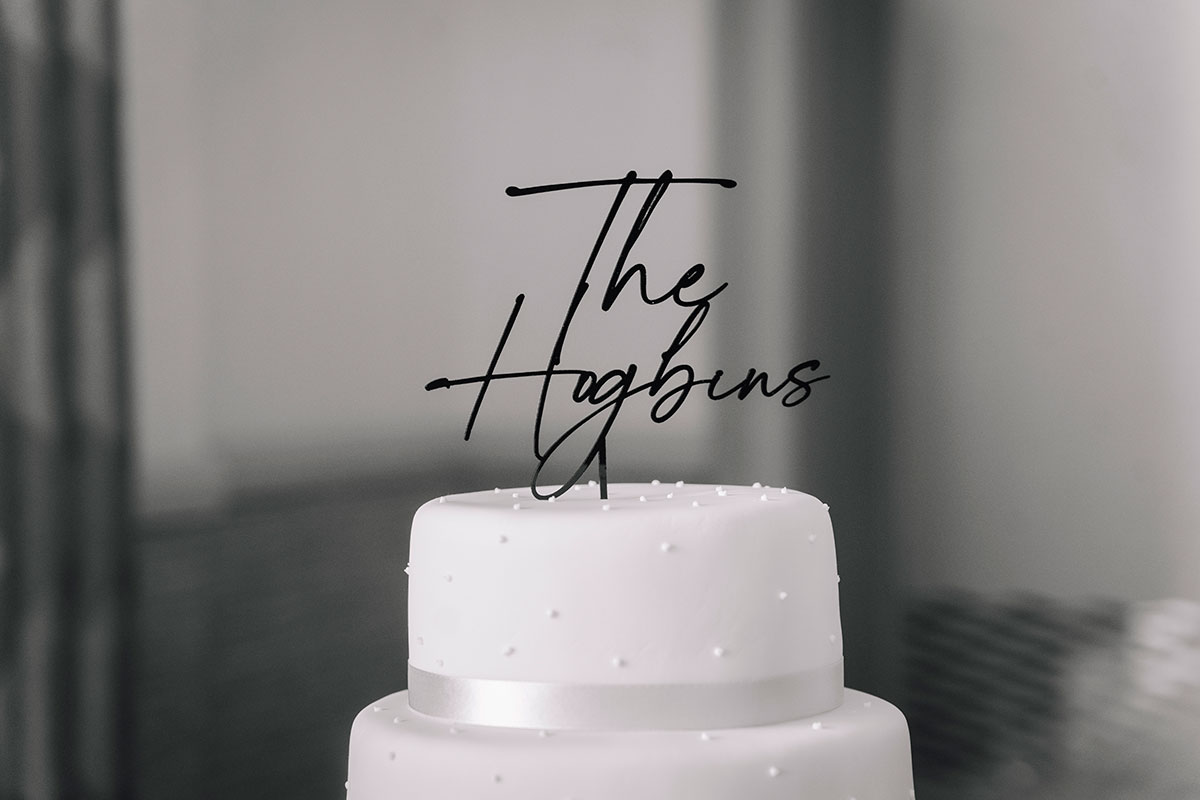 Minimalist white wedding cake with topper displayed during the reception