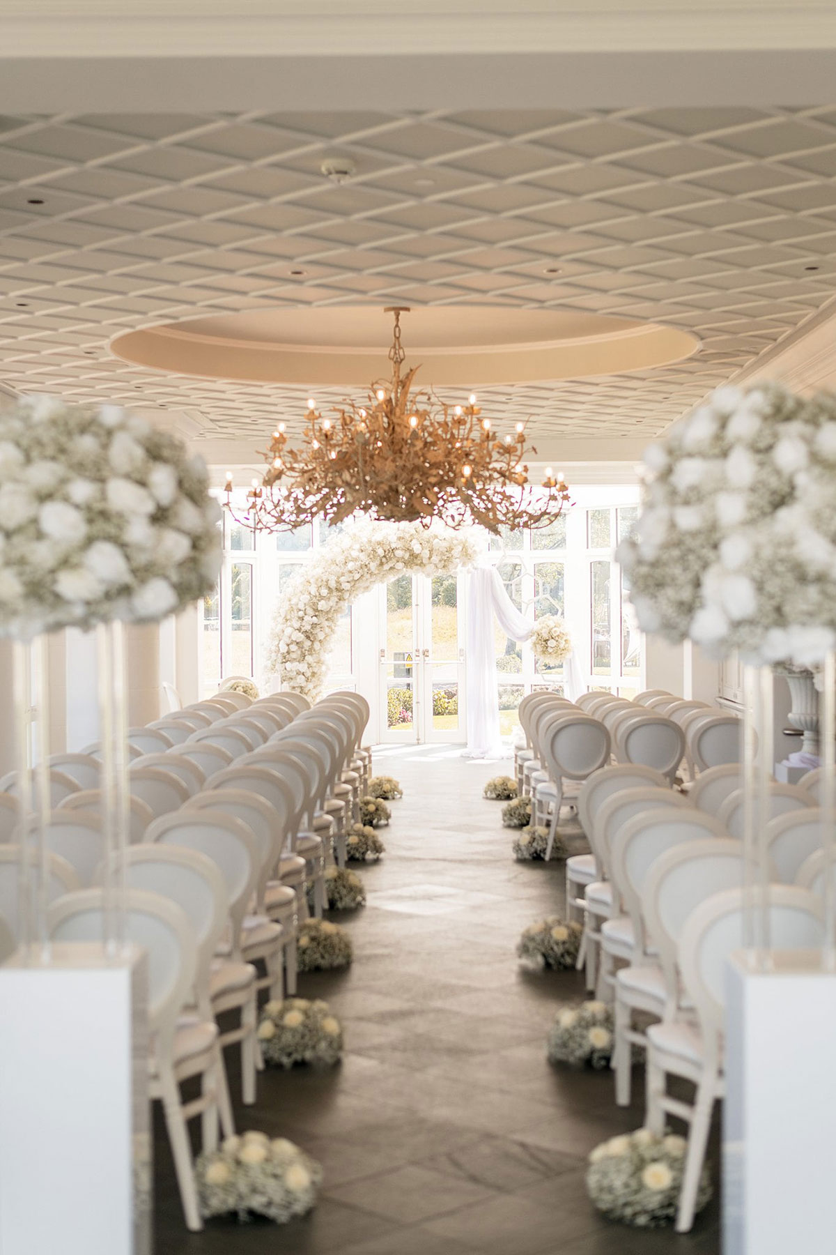 Elegant conservatory ceremony setup with white floral arch and aisle styling at Old Course Hotel wedding venue in St Andrews.