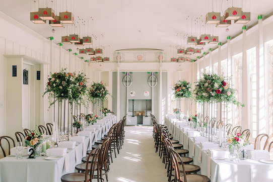 Charles Rennie Mackintosh-designed Music Room at House for an Art Lover set for dinner with long tables, elegant dark wood chairs and raised flower arrangements