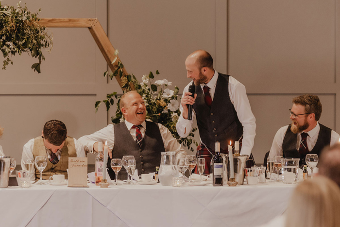 Groom hangs his head as guests laugh during speeches