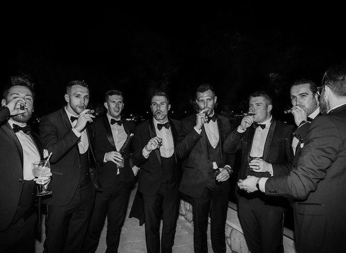 men in formal attire and bow ties puff on cigars