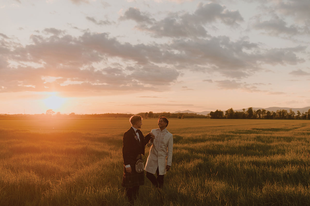newlyweds laughing together in open countryside at sunset after intimate Falkirk farm wedding