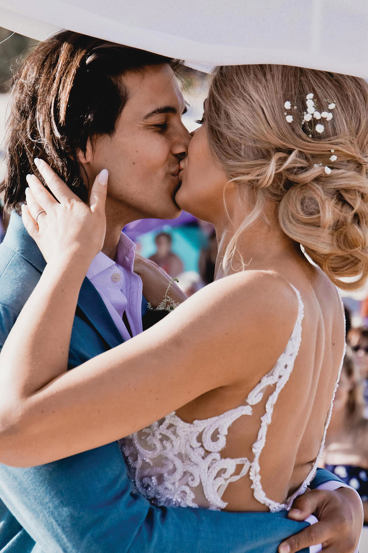 Bride and groom kissing during outdoor wedding ceremony in bright sunlight