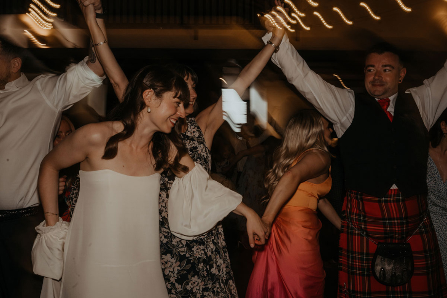 Bride is taken on to the dancefloor by a bridesmaid