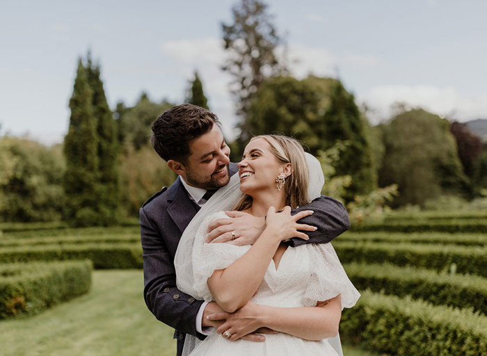 a bride and groom embracing and smiling in the garden at Achnagairn Castle