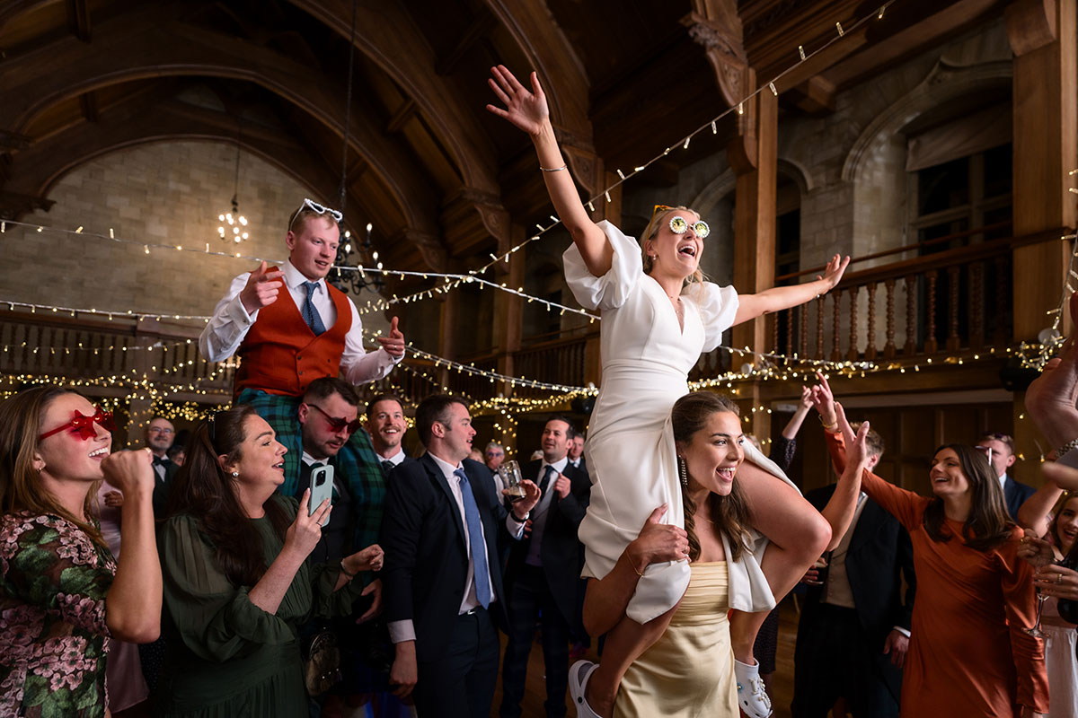 bride and groom on top of guests shoulders during wedding reception at achnagairn castle