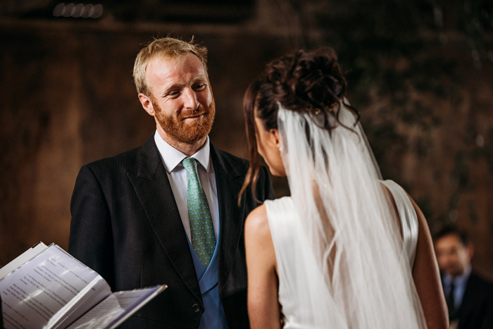 A Person Wearing A Green Tie Blue Waistcoat And Black Jacket Looking At Another Person Wearing A Veil