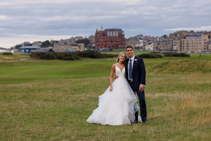 A joyful bride and groom sharing a moment on the Old Course Hotel golf course with the St Andrews cityscape in the background