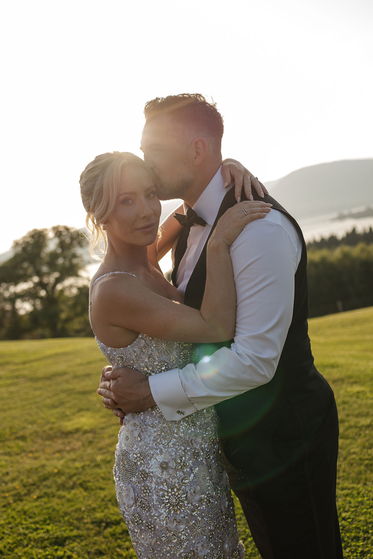 Bride and groom embrace at sunset during portraits at Boturich Castle with Loch Lomond in the background.