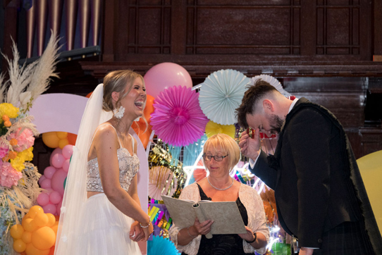 Bride and groom laugh during their wedding ceremony at St Luke's Glasgow