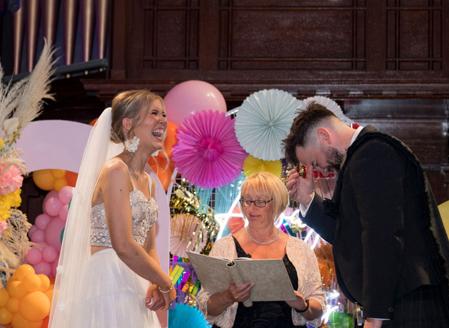 Bride and groom laugh during their wedding ceremony at St Luke's Glasgow