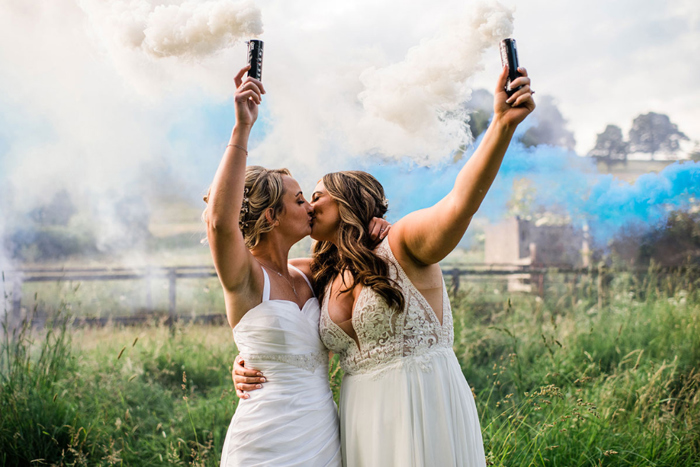 Brides hold smoke bombs during couple portraits