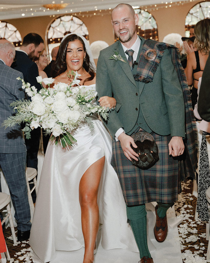 bride and groom walk down the aisle after saying their vows and smile towards the camera