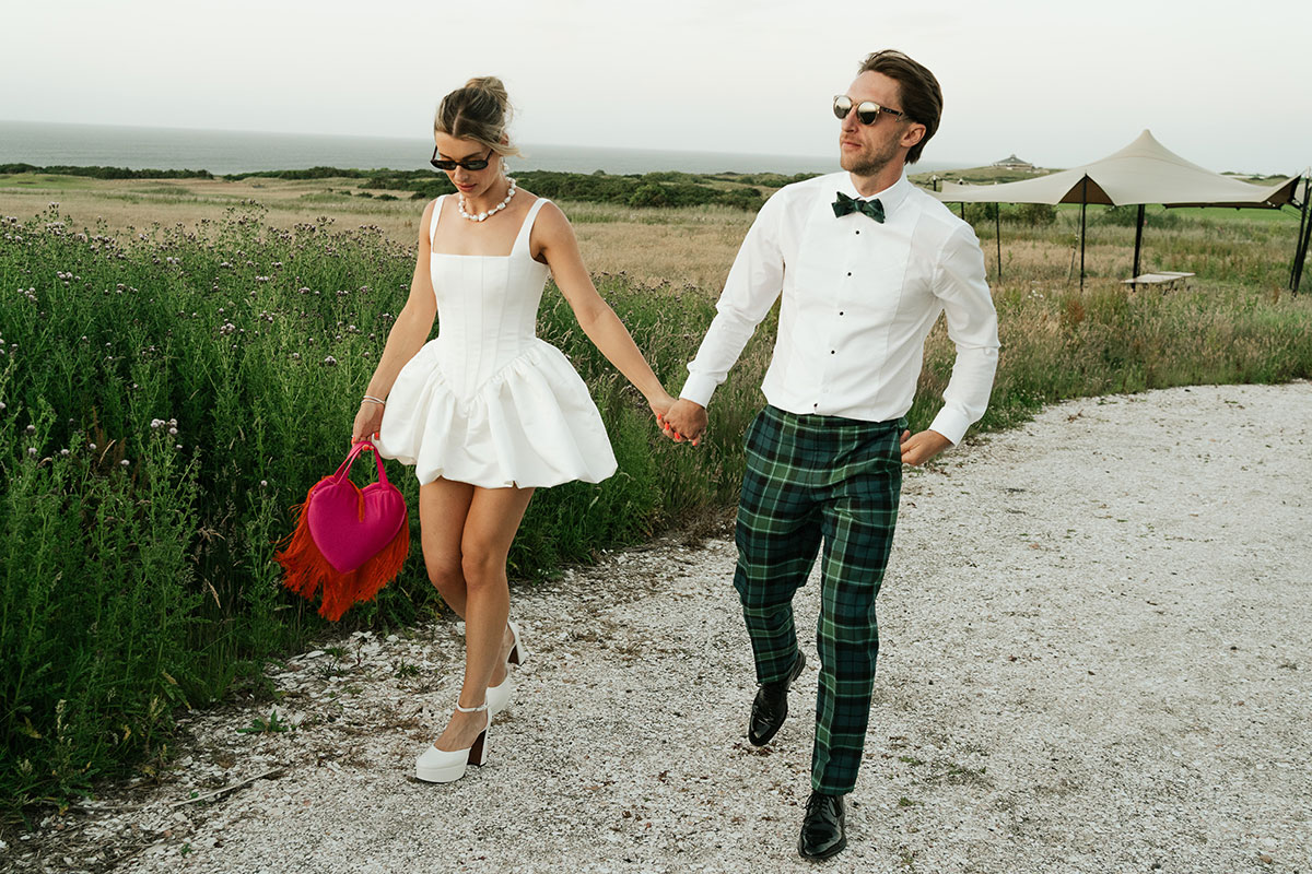 bride wearing short bubble-hem white dress walking with groom wearing tartan trews at Kinkell Byre.
