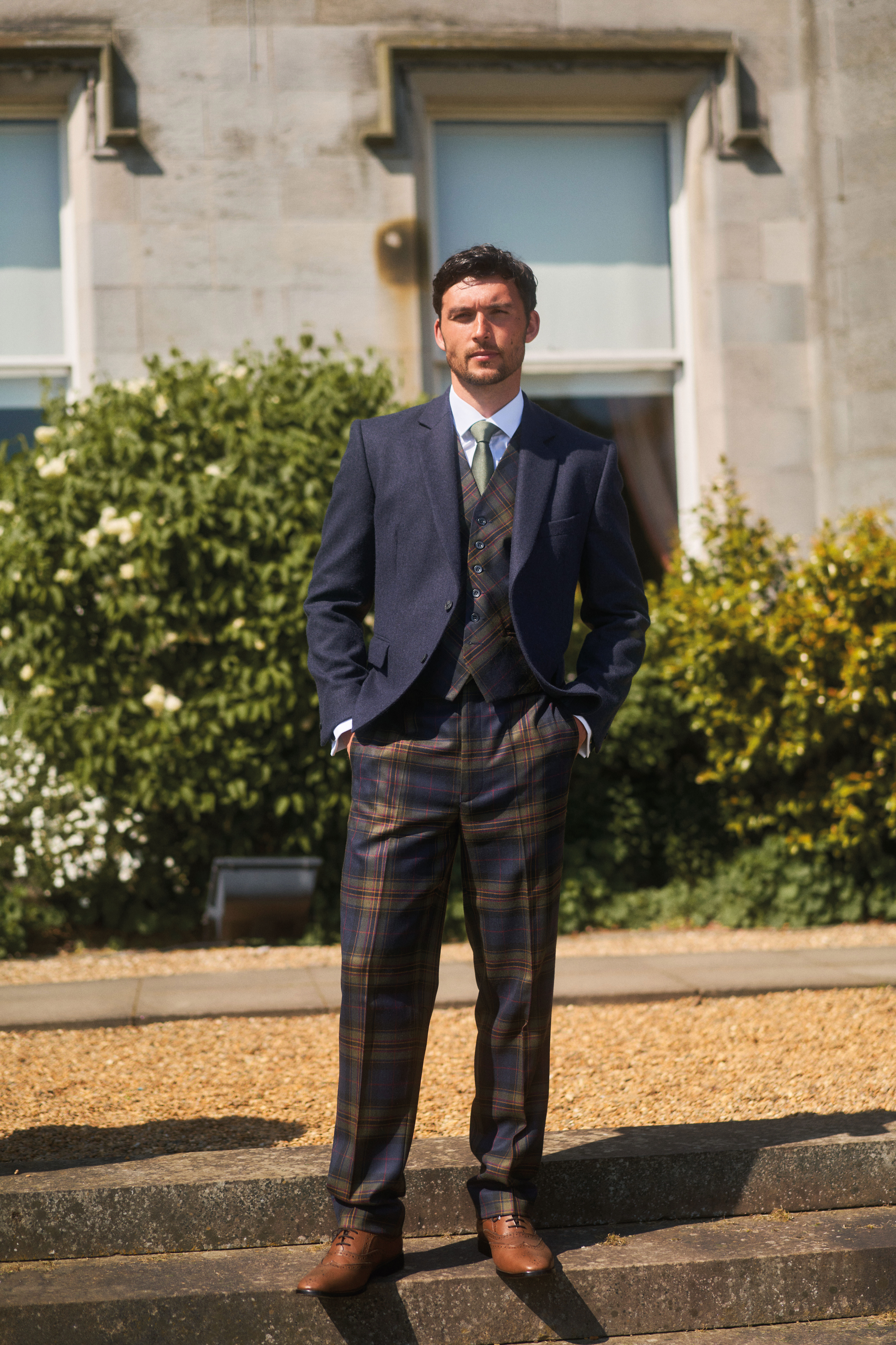 groom stares directly at camera while wearing navy jacket paired with mccalls highlandwear's new noble print tartan trews