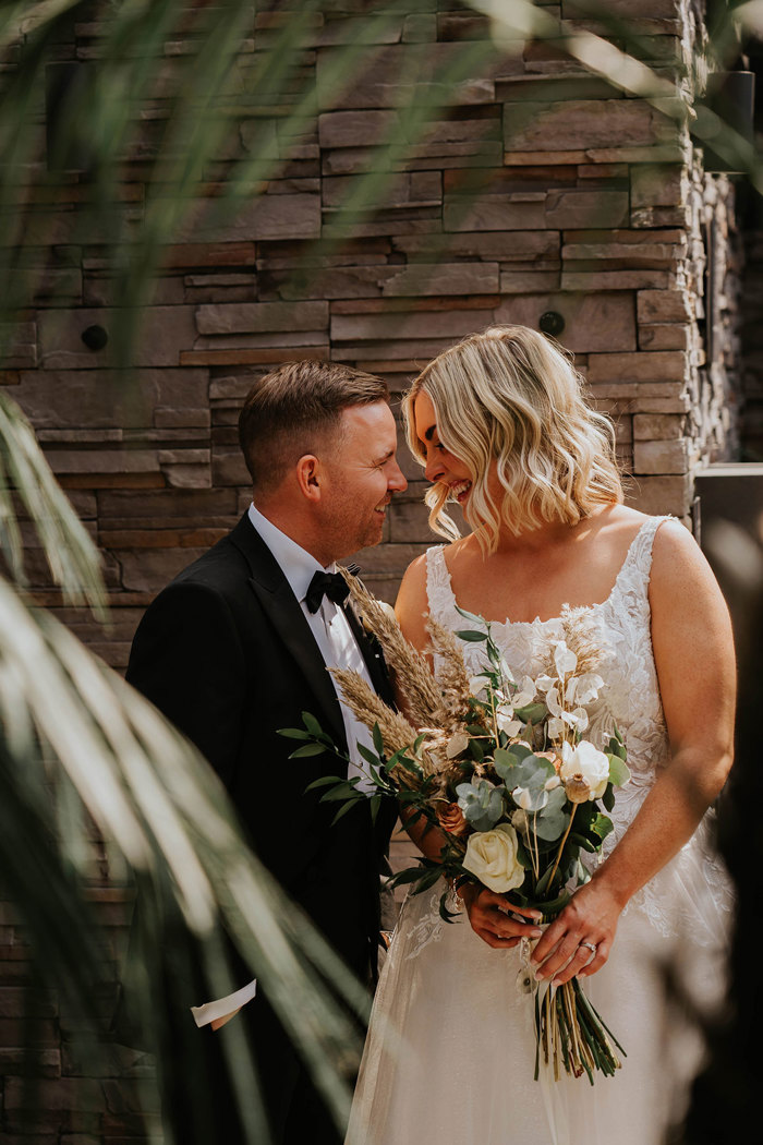 A bride and groom in wedding attire posing in a garden setting