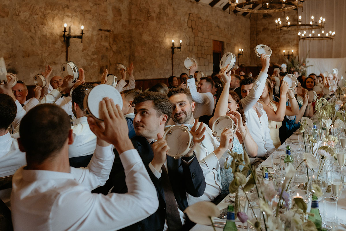 Wedding guests shaking personalised tambourine favours during Rosebery Steading wedding breakfast in Midlothian.