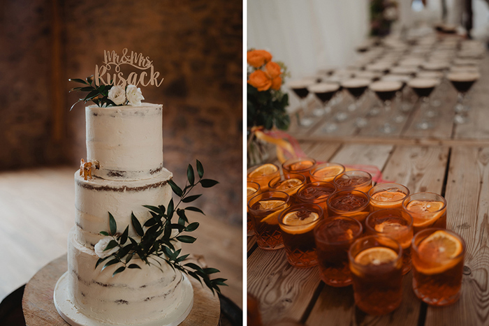 A Ivory Buttercream Wedding Cake And Glasses With Negronis Garnished With Orange On A Wooden Table