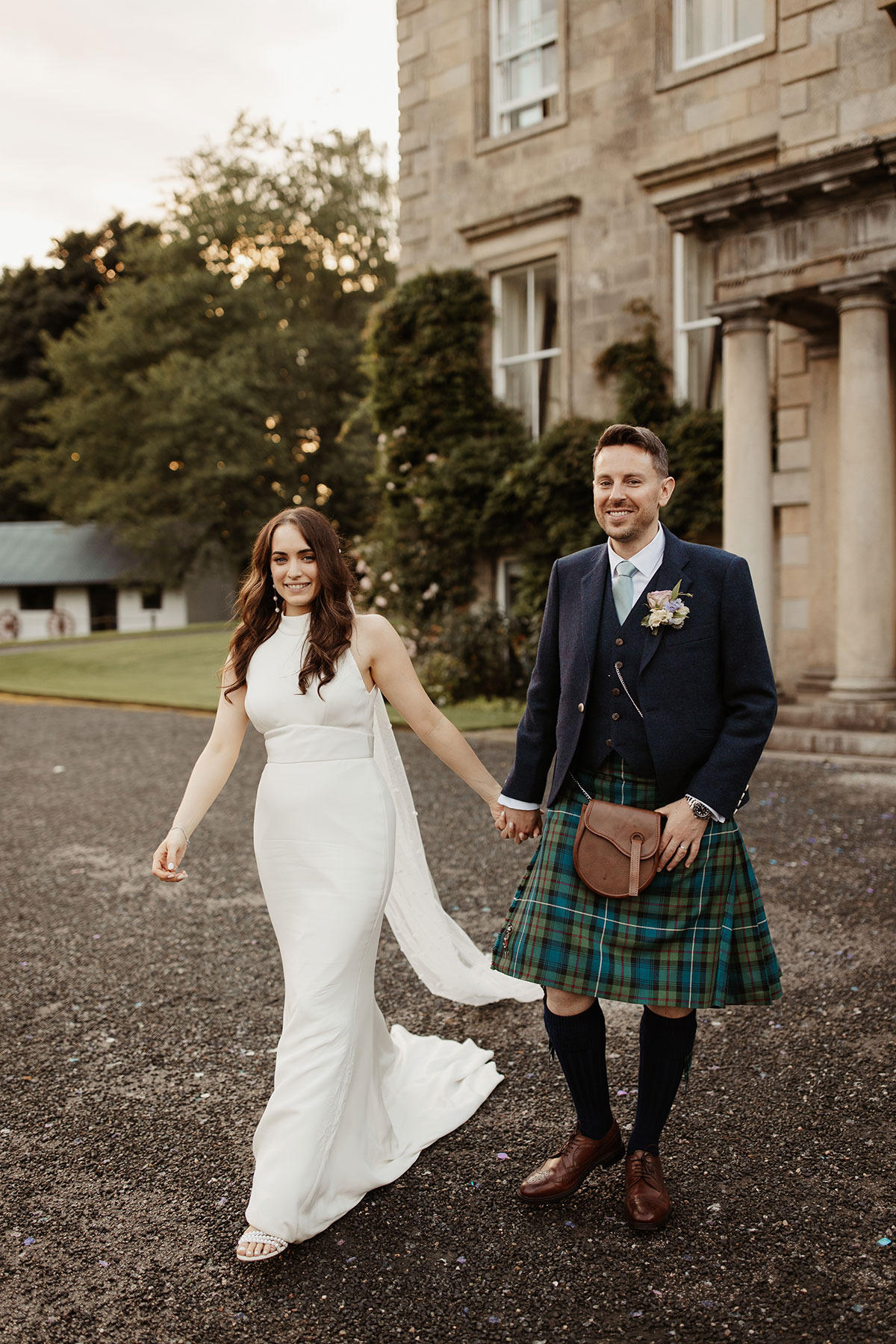 a bride and groom walking hand in hand outside Netherdale House