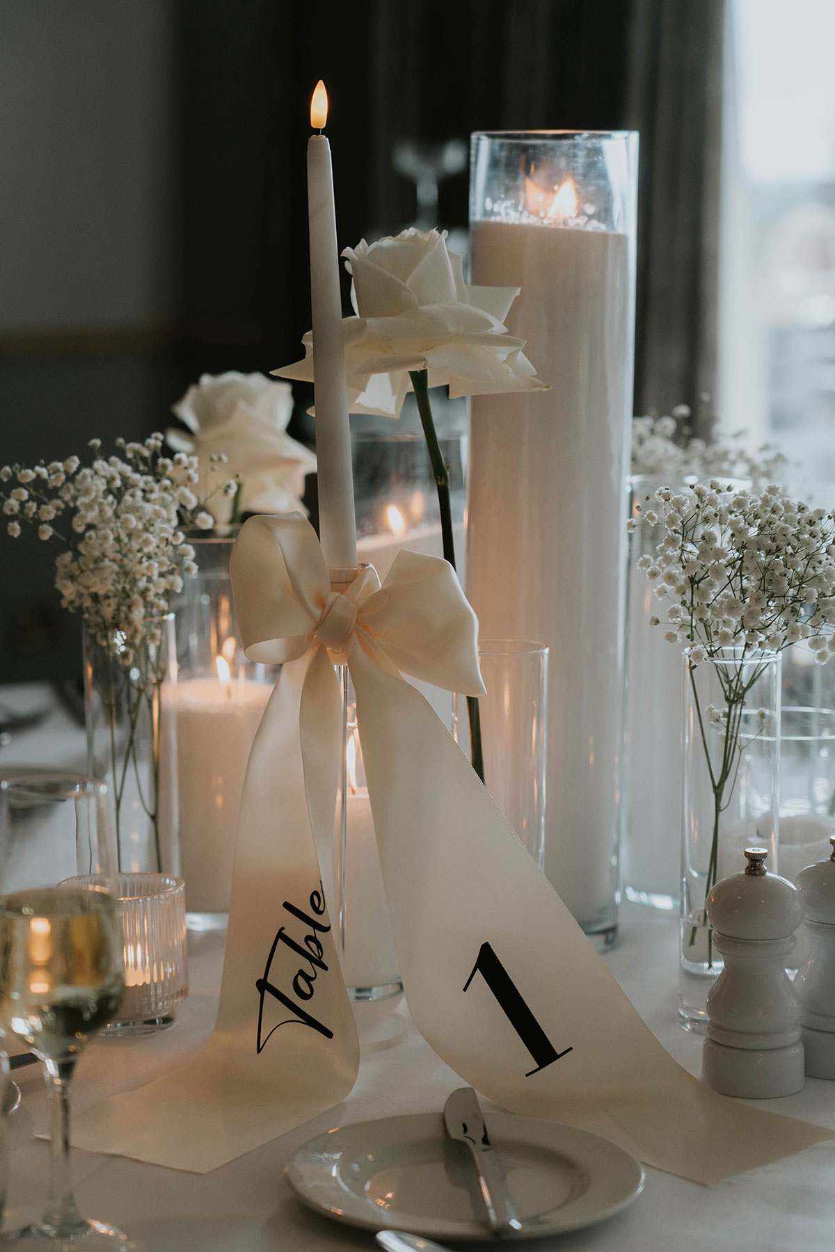  Monochrome wedding table centrepiece with white roses, glass candles and ribbon-tied table number at Brisbane House Hotel