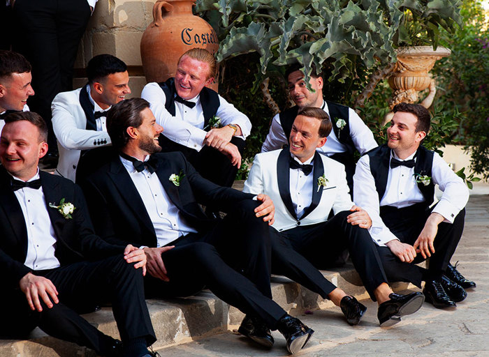 a group jovial of men wearing suits sitting on stairs