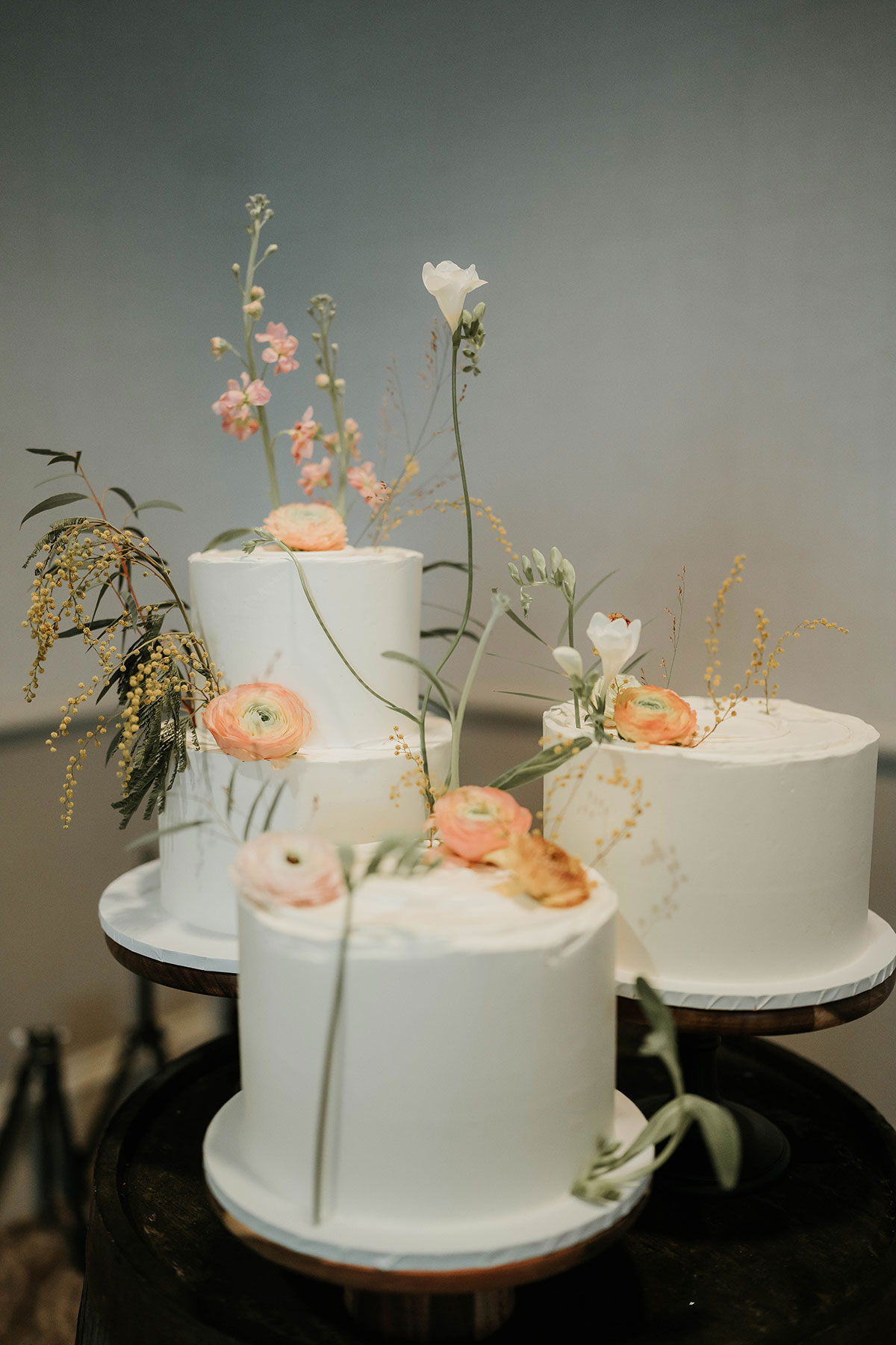Three-tiered white wedding cakes decorated with pastel spring flowers