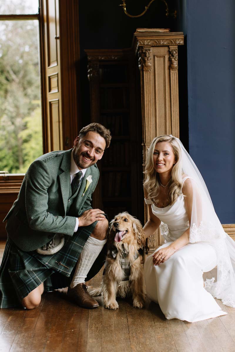 Bride Lia and groom Louis pose with dog Bertie inside Cambo House on their wedding day.