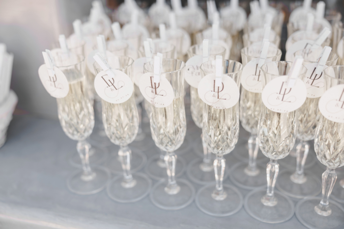 Rows of crystal champagne flutes filled with liquid and with round D&L emblem on paper circles