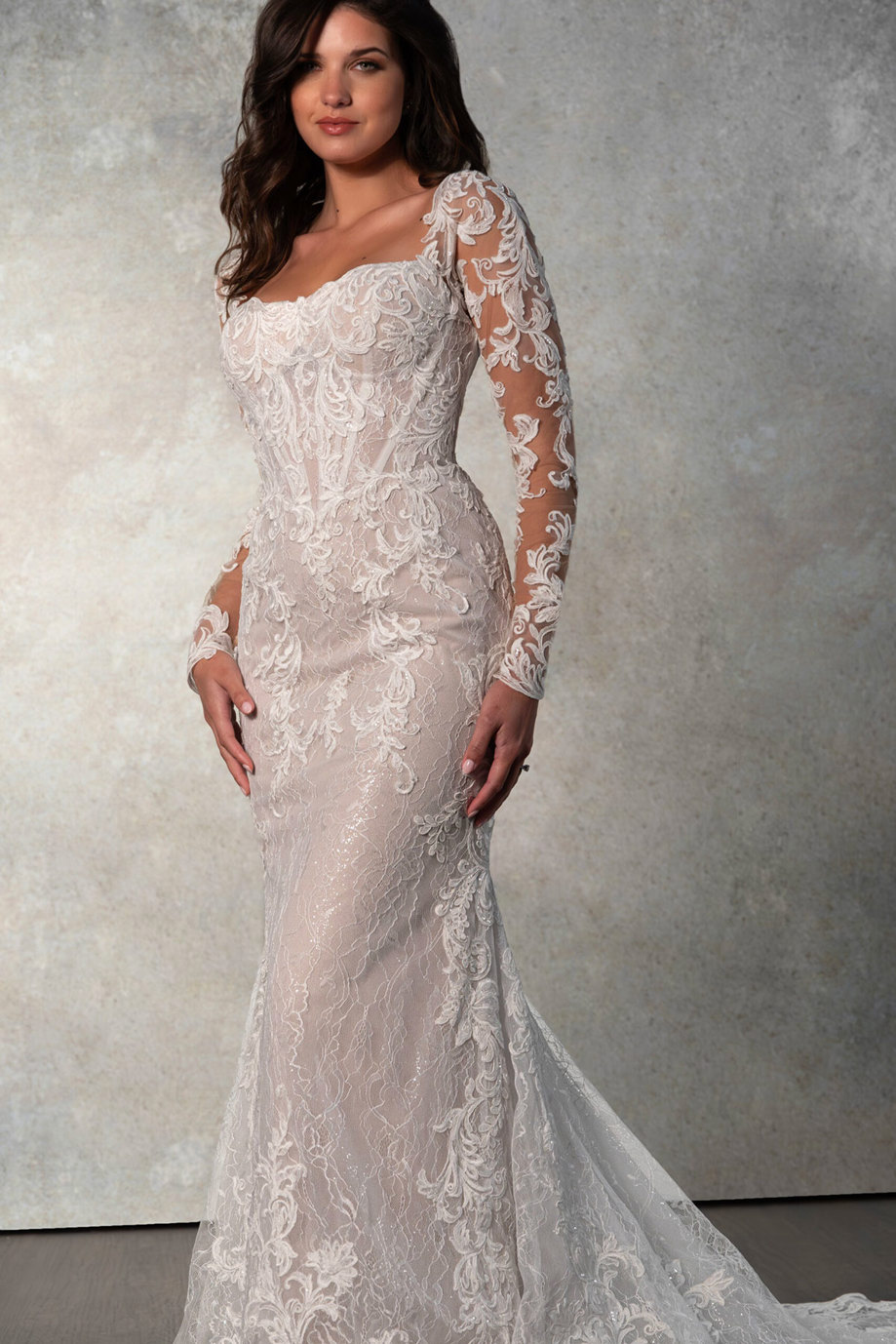 brunette model wears long sleeve floral embroidered wedding dress with a mermaid shape 