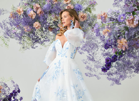 bridal model wears an off the shoulder puff sleeve gown covered in painted blue florals