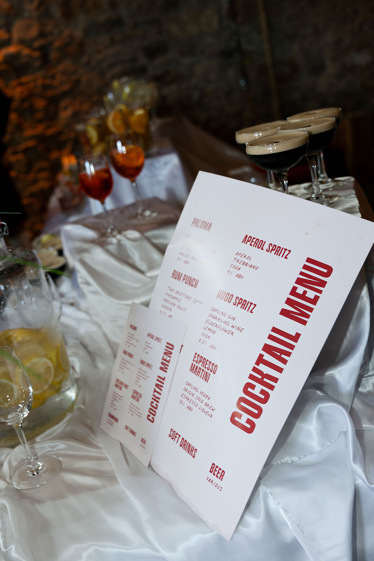 Custom cocktail menu featuring palomas, aperol spritzes and espresso martinis displayed at the drinks station during a Mexican-inspired wedding reception.