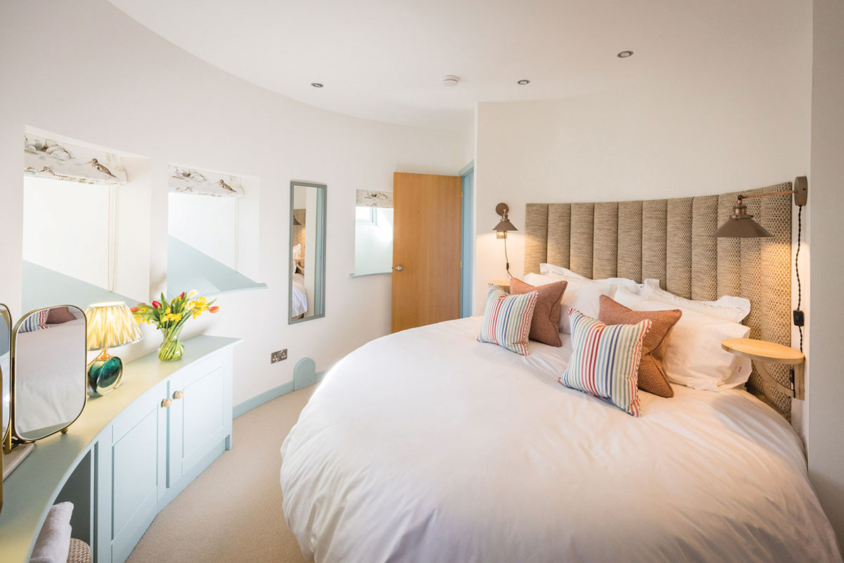 Bright circular bedroom inside the Dalmeny Water Tower at Rosebery Steading, featuring a king-size bed and soft coastal-inspired décor