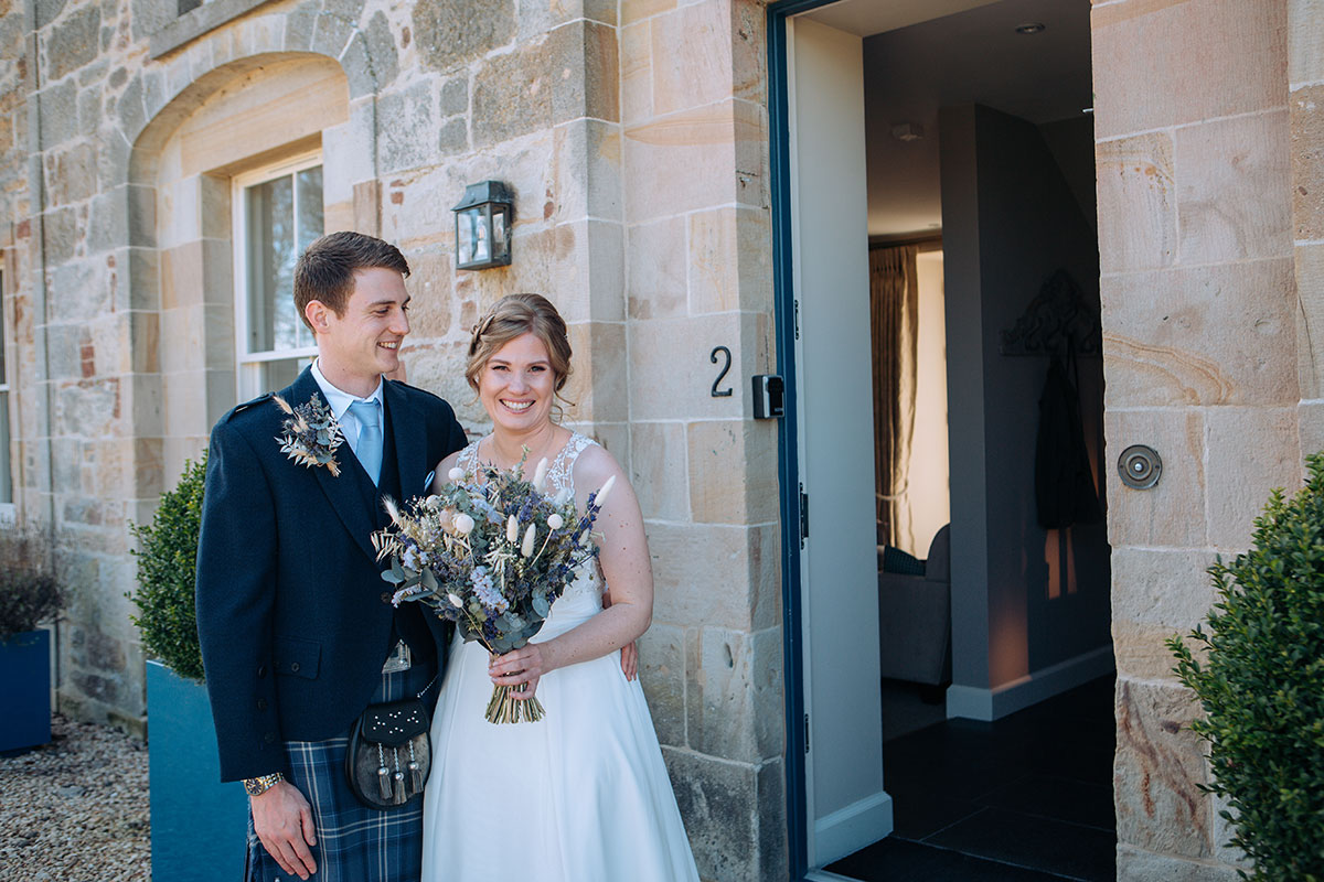 Bride and groom pose after their ceremony outside Newhall Mains