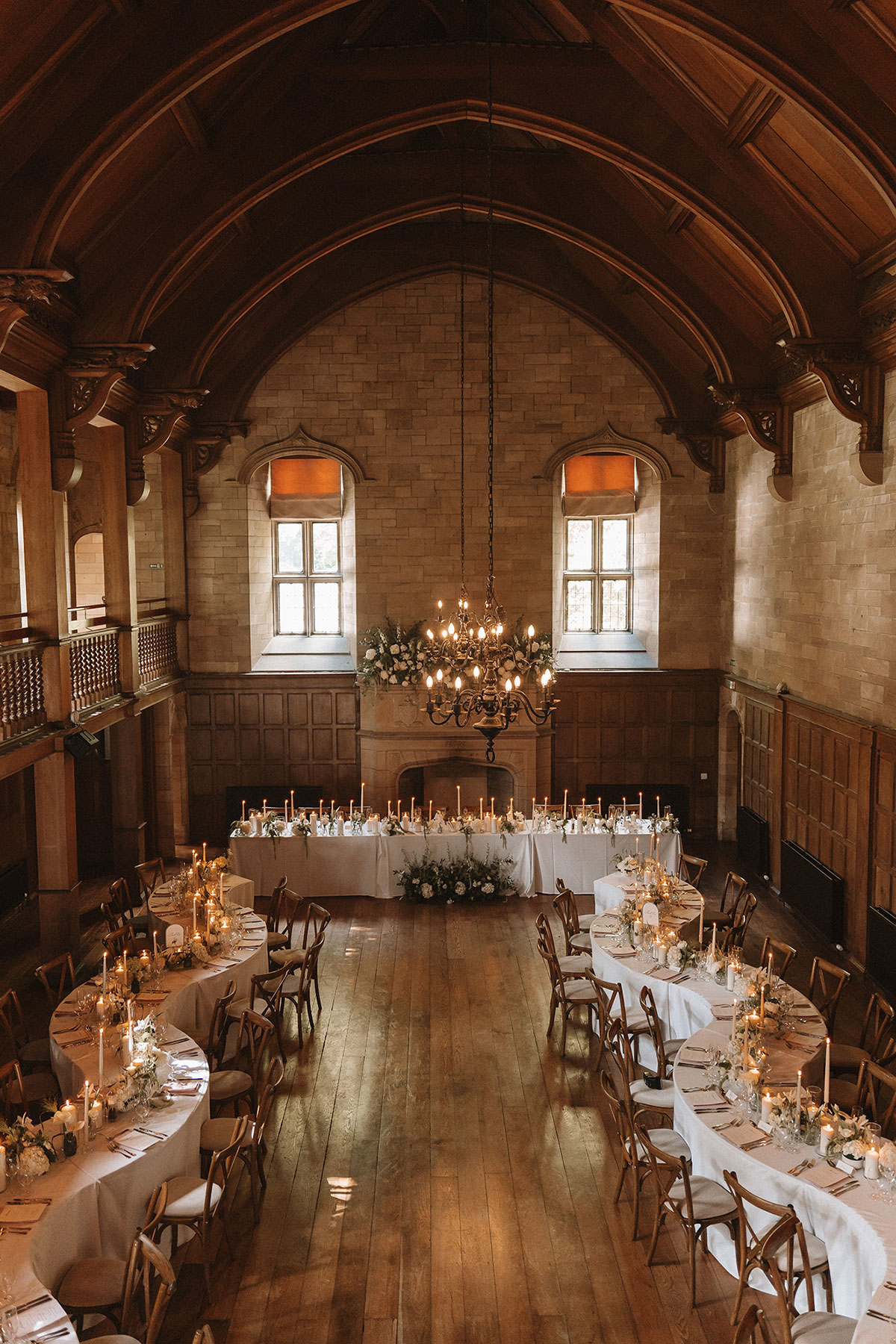 A wedding reception in a vaulted ballroom featuring curved banquet tables, candlelight and classic wood details.
