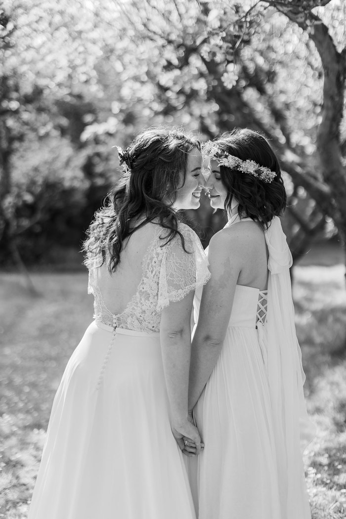 two brides kissing below trees