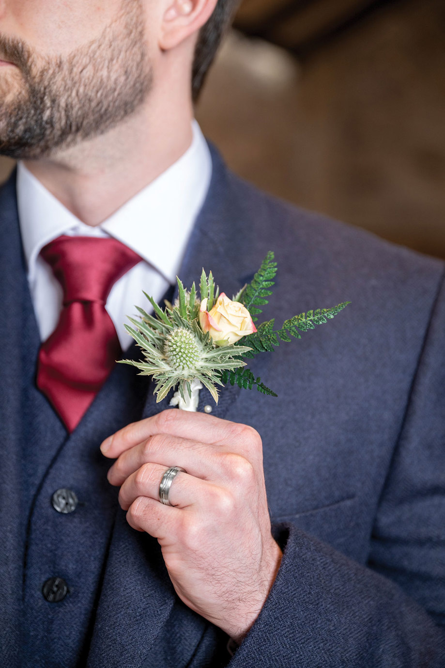 a hand on a thistle and rose buttonhole