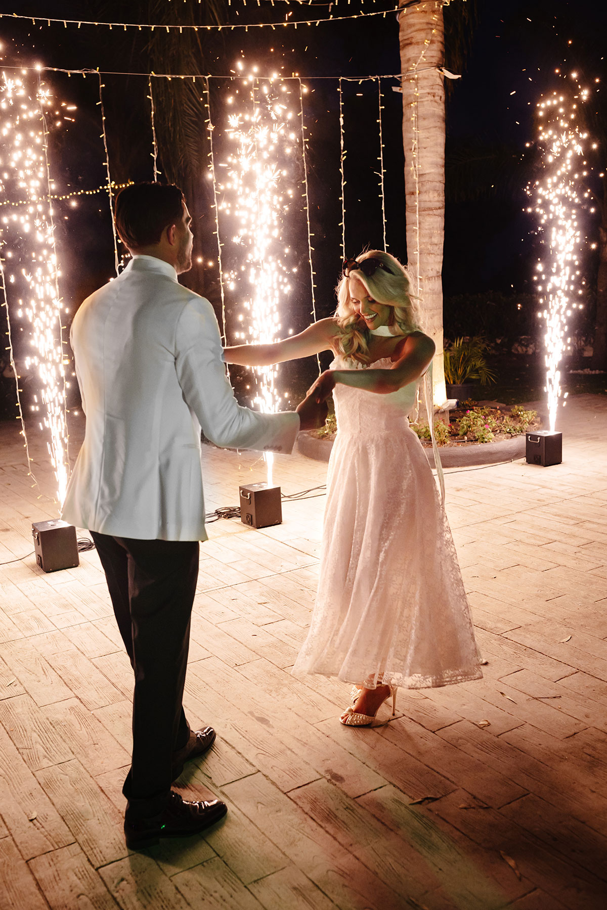 Newlyweds twirl on the dance floor under sparkling fireworks during their evening reception