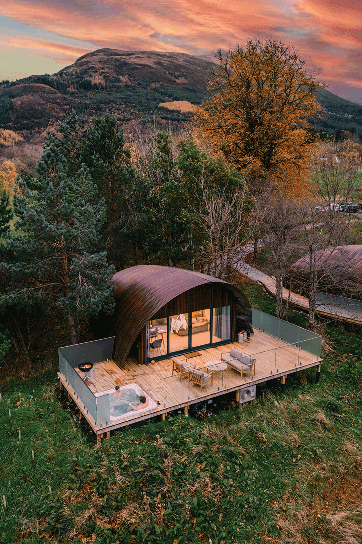Luxury woodland cabin with private hot tub in Glencoe surrounded by autumn scenery and Scottish mountain views at sunset