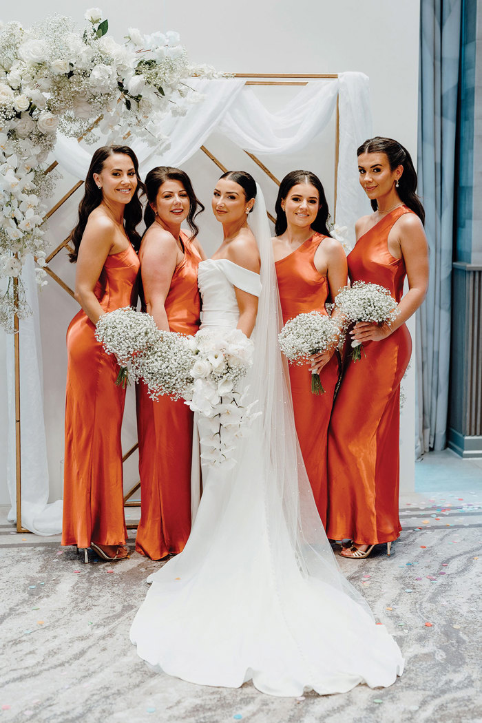 A bride and a group of women in orange dresses