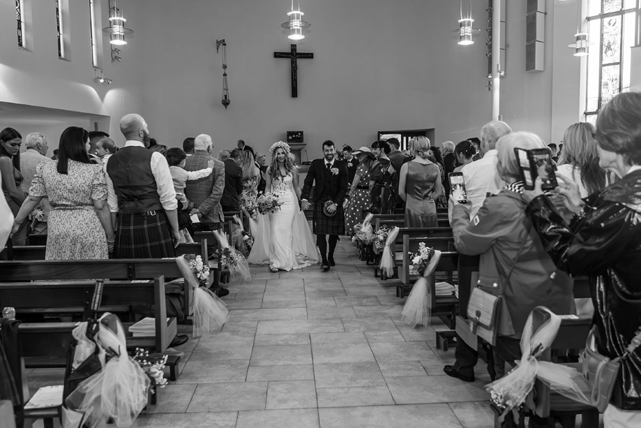 Bride and groom walk up the aisle of the church as a married couple