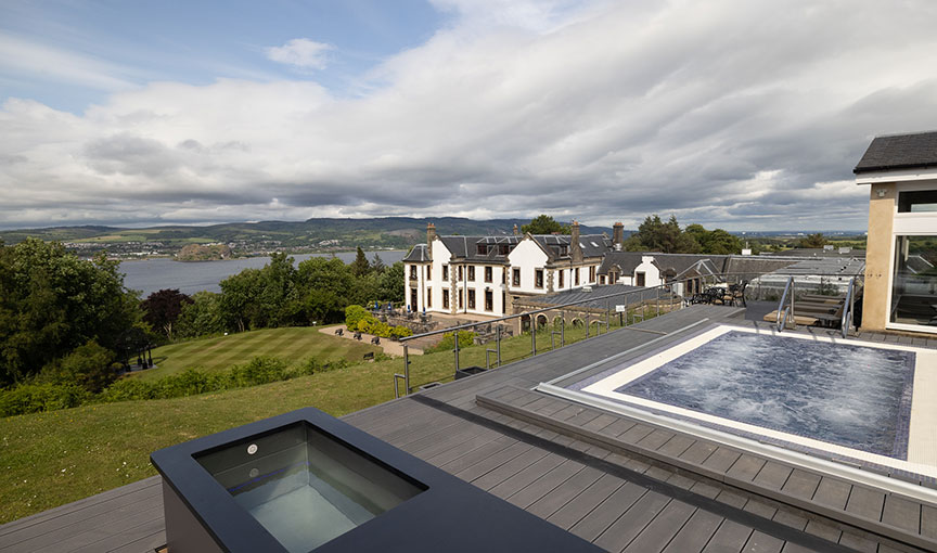 Outdoor spa terrace at Gleddoch with hot tubs overlooking the River Clyde and rolling hills.