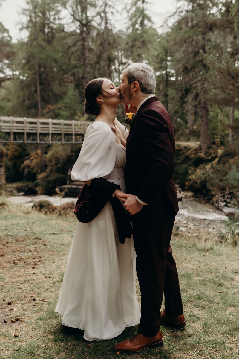 a bride and groom kissing by River Quoich wooden bridge on mar lodge estate